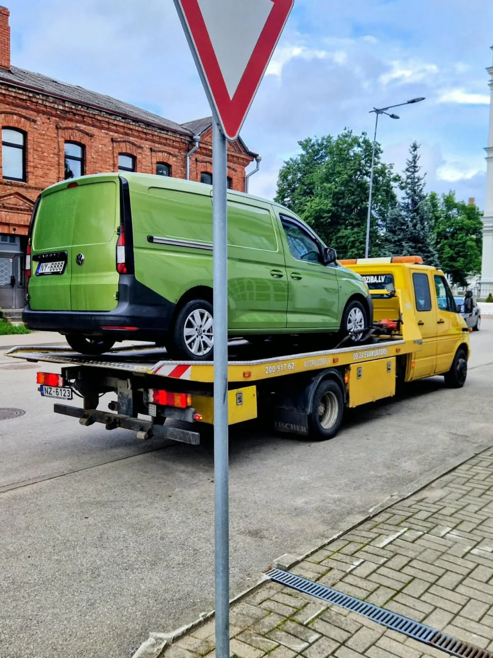 Green minivan loaded on a tow-truck platform in Daugavpils